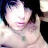 Person with dark hair and chest tattoo.