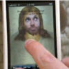 Finger touching phone screen with Jesus image.