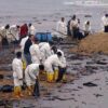 People cleaning oil spill on beach.