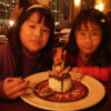 Two children enjoying dessert at restaurant.