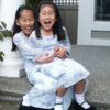 Two girls laughing on porch steps.