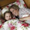 Mother and daughter smiling in floral bedding.