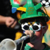 Person with colorful hat blowing vuvuzela.