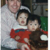 Man with two young children in red outfits.