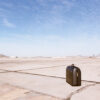 Suitcase on empty airport runway under sky.