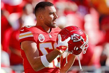 Tight end Travis Kelce seen here looking at his helmet, annoyed to see that it doesn’t have Taylor’s face on it. “Hey, Coach Reid, what gives? And you forgot to get it signed by Taylor. What’s up with that, dude?”